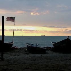 Boat moored on sea against sky during sunset