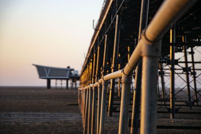 Built structure at beach against clear sky during sunset