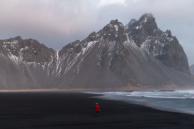 Rear view of person on snowcapped mountain against sky