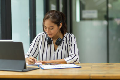 Young woman using phone while sitting on table