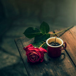 Close-up of red rose and coffee cup on table