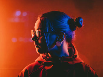 Close-up of young woman wearing eyeglasses while standing outdoors at night