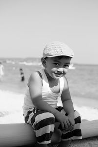 Portrait of boy sitting on beach against sky