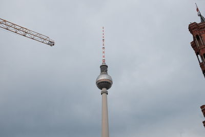 Low angle view of fernsehturm against cloudy sky