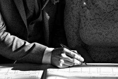 Midsection of man writing in book