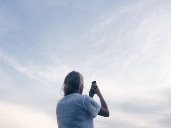 Low angle view of woman photographing sky