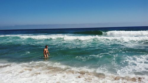 Rear view of man on beach against clear sky