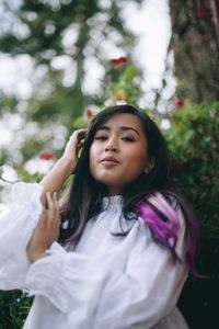 Portrait of a young woman standing against plants