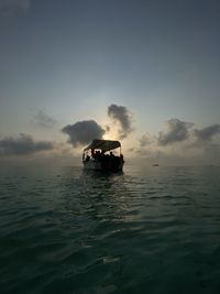 Boat sailing in sea against sky at dusk