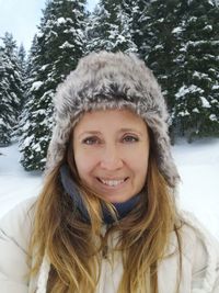Portrait of smiling woman in snow against trees