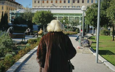 Rear view of senior woman on walkway against building