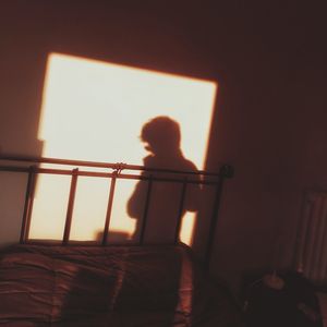 Rear view of woman standing on bed at home