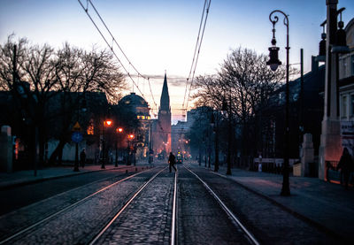 Railroad tracks amidst buildings against sky at dusk