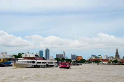 Boats in sea against sky in city