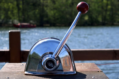 Close-up of coin-operated binoculars on table by lake