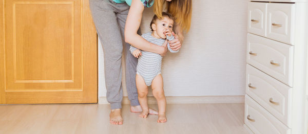 Midsection of mother and son standing on floor