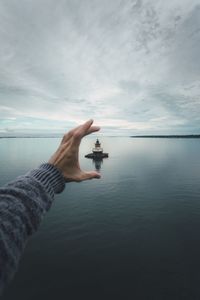 Close-up of hand holding sea against sky