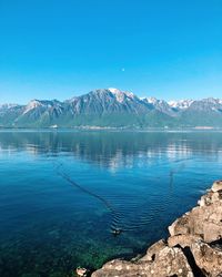 Scenic view of lake and mountains against blue sky