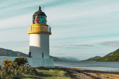 Lighthouse by sea against sky