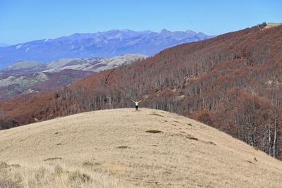 Rear view of man on arid landscape against sky