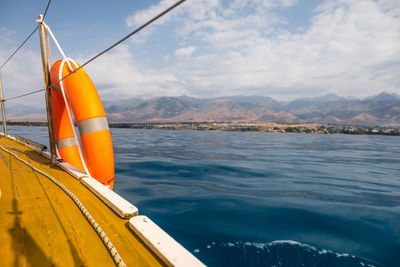 Sailboat sailing on sea against mountains