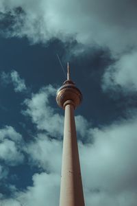 Low angle view of communications tower against cloudy sky