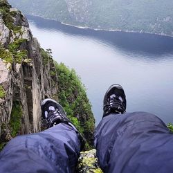 Low section of man standing on cliff by sea