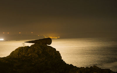 Scenic view of rocks on beach against sky during sunset