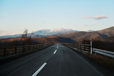 Road leading towards mountains against sky