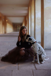 Portrait of young woman sitting on the floor with dalmatian