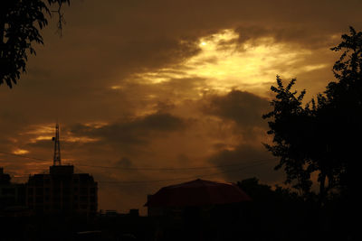 Low angle view of silhouette trees against cloudy sky