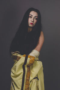 Portrait of woman standing against black background