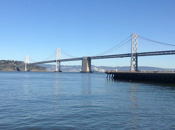 Suspension bridge over river against blue sky