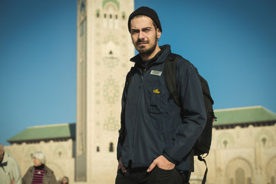 Portrait of young man standing against sky