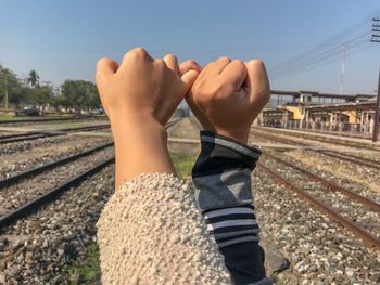Cropped hands doing pinky promise against rail road tracks