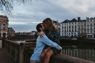 Friends standing on bridge over canal against buildings