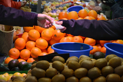 Cropped hands of customer paying to vendor at market stall