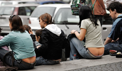Men and women sitting on sidewalk in city