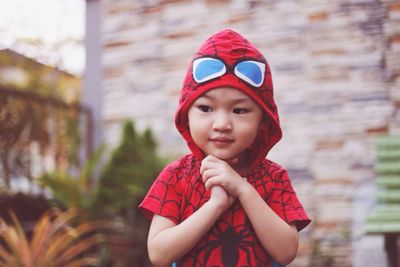 Thoughtful by wearing spider man jacket while standing with hands clasped outdoors
