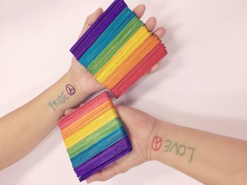 Cropped image of people holding colorful popsicle sticks against wall