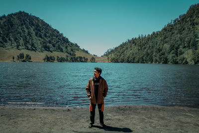 Full length of man standing on riverbank against sky