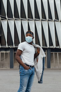 Portrait of young man wearing sunglasses standing against built structure