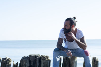 Side view of young man standing against sea