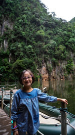 Portrait of young man standing against waterfall