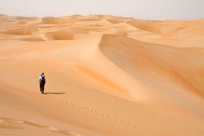 Full length of man walking on sand dune