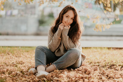 Portrait of woman sitting on dry leaves