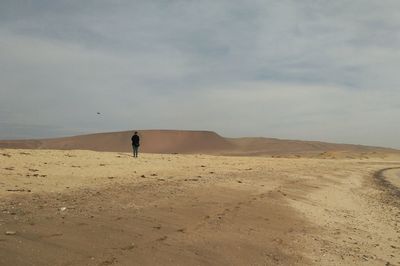 Scenic view of desert against sky with a person