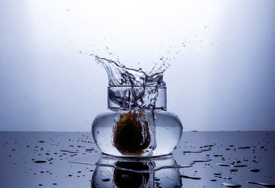 Close-up of glass splashing water against white background
