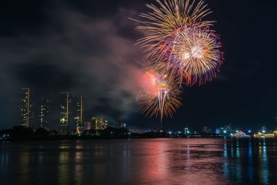 Low angle view of firework display over river at night