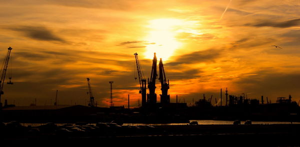 Cranes against sky during sunset